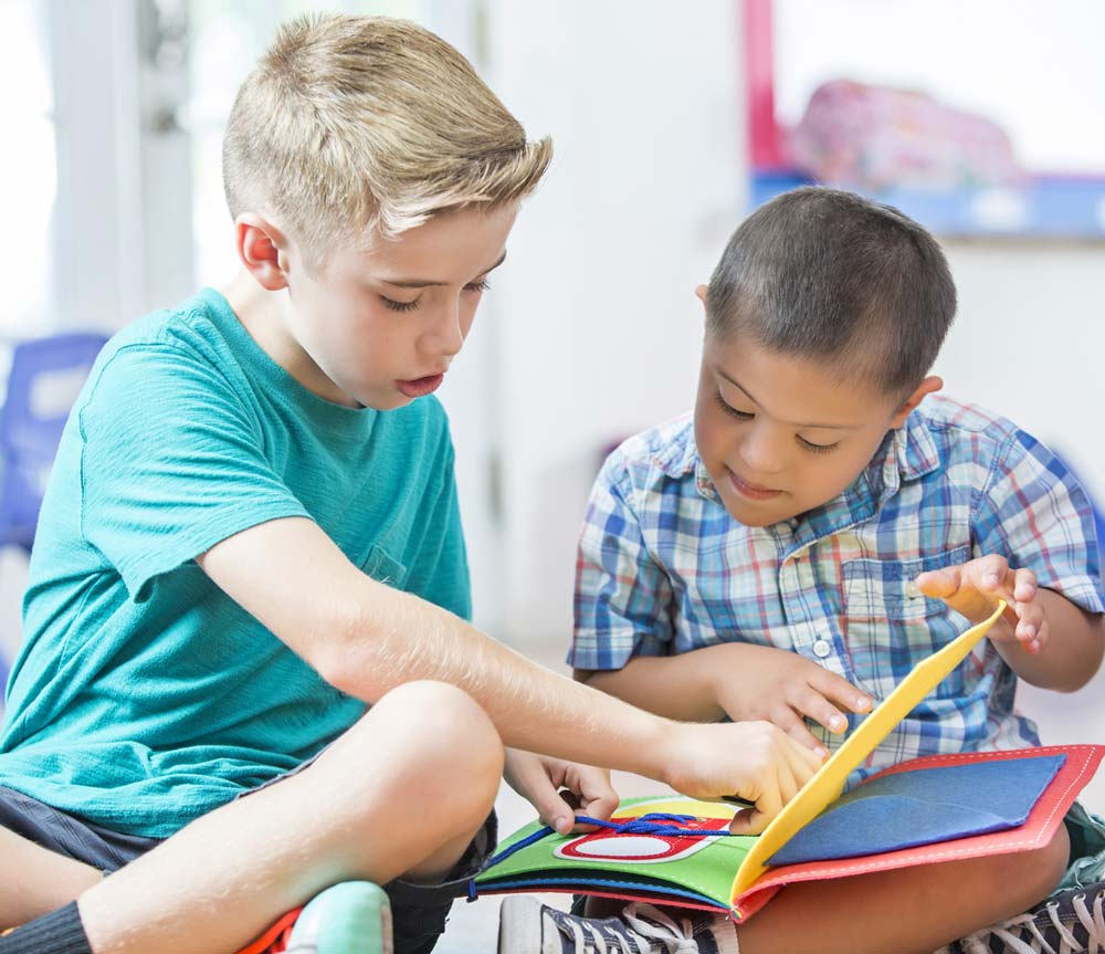 boy reading to boy with Downs Syndrome