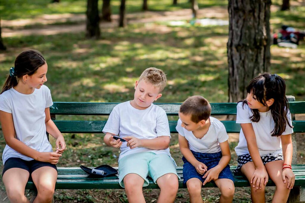boy with diabetes checking blood sugar with friends watching