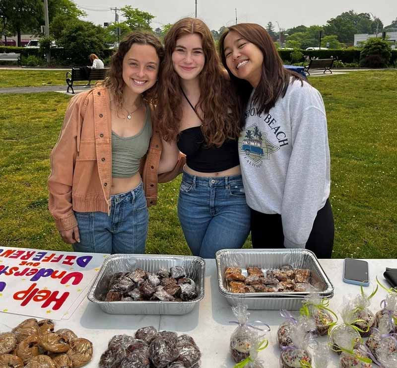 Newton South High School juniors pose behind table fundraising for UOD